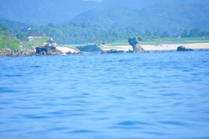 岩場の向こうの砂浜では、高校生が遊んでいます。